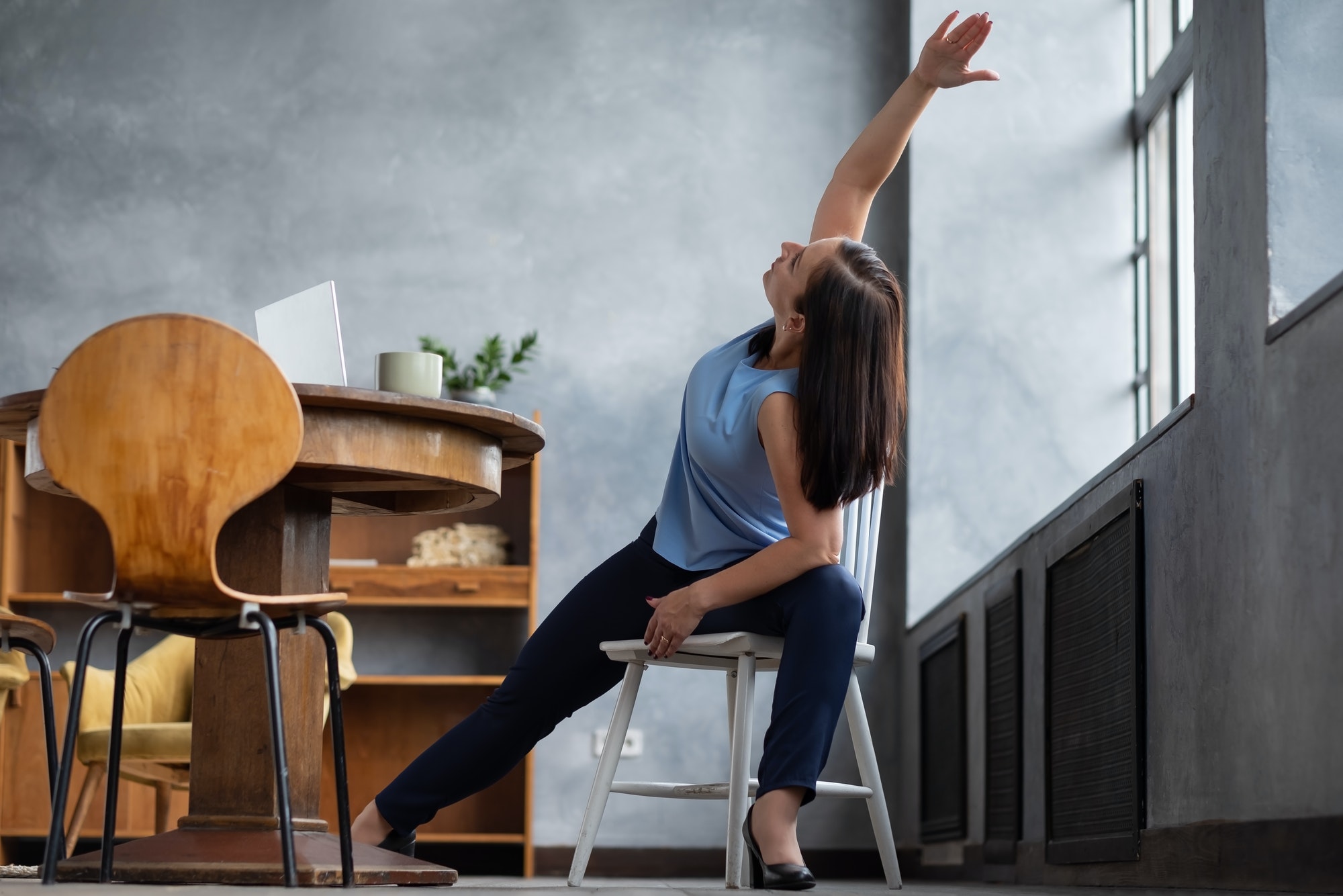 Woman practicing yoga using chair, stretching in Extended Side Angle exercise
